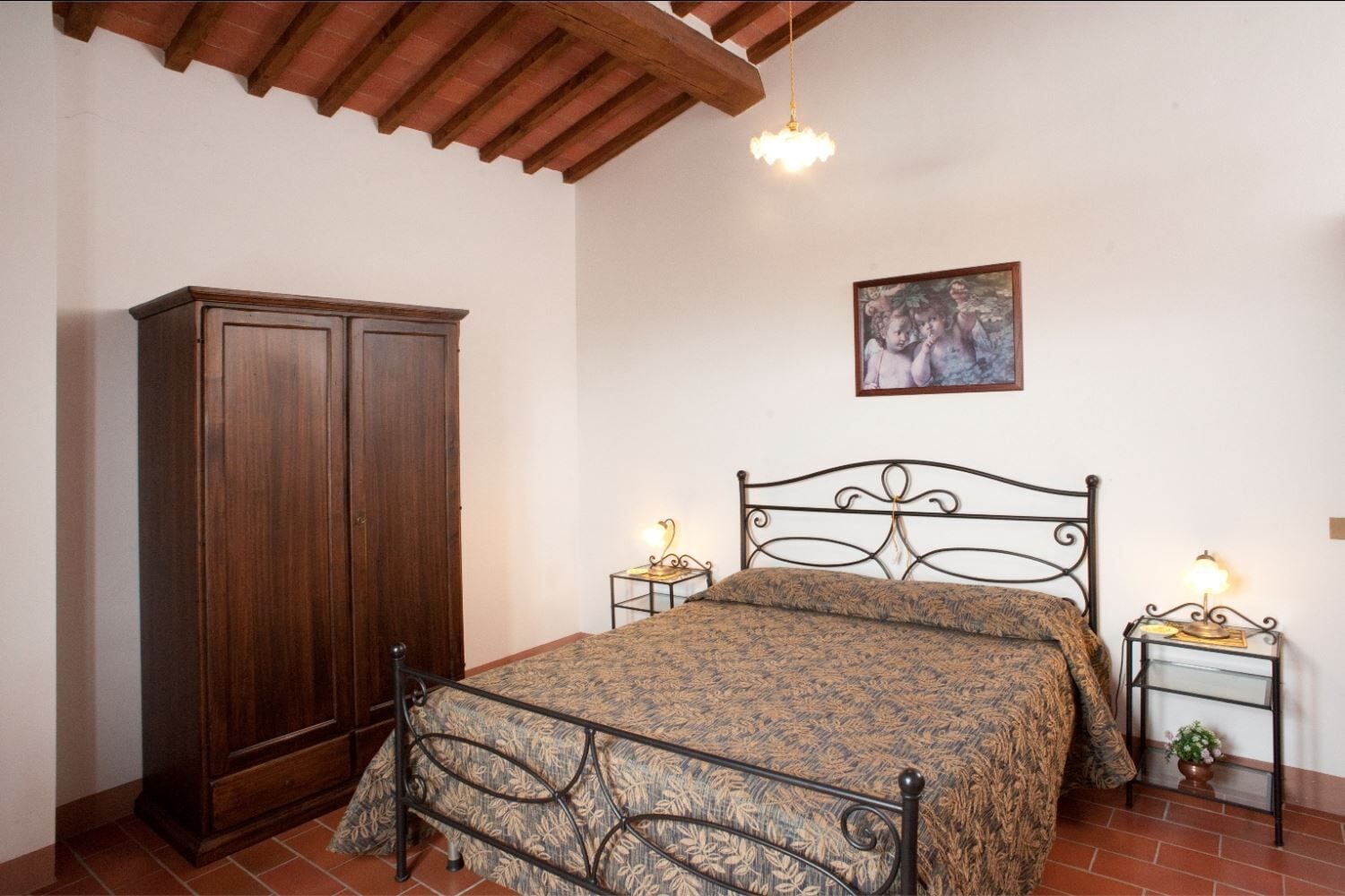 Een slaapkamer met een bed, een kledingkast, een schilderij aan de muur en een plafondventilator.