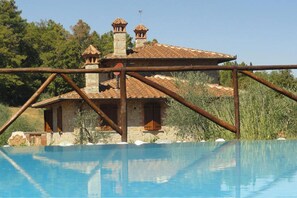 A stone villa with a tiled roof, a swimming pool, and a rustic metal fence. - La Casetta nel Bosco (Sinalunga)