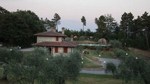 A rustic stone building with a tiled roof, surrounded by olive trees and a landscaped garden with a pathway. - La Casetta nel Bosco (Sinalunga)