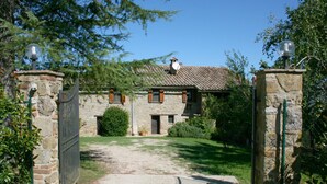 A stone building with a tiled roof, a gated entrance, and a well-maintained lawn. - Monte del Lago (Magione)