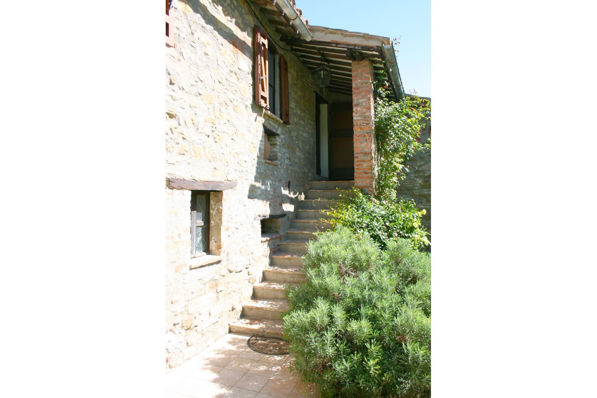 A stone building with a wooden staircase leading to a covered entrance.