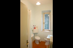 A small bathroom with a toilet, sink, and window.