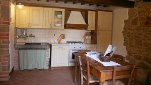 A rustic kitchen with a stone wall, wooden beams, and a tiled backsplash.