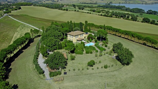 An aerial view of a countryside property with a large house surrounded by lush green fields and a swimming pool. - Poggio Falcone (Castiglione del Lago)