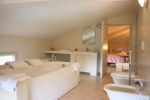 A bathroom with a bathtub, a sink, and a toilet. There is a mirror above the sink and a towel rack beside the bathtub. - Poggio Falcone (Castiglione del Lago)