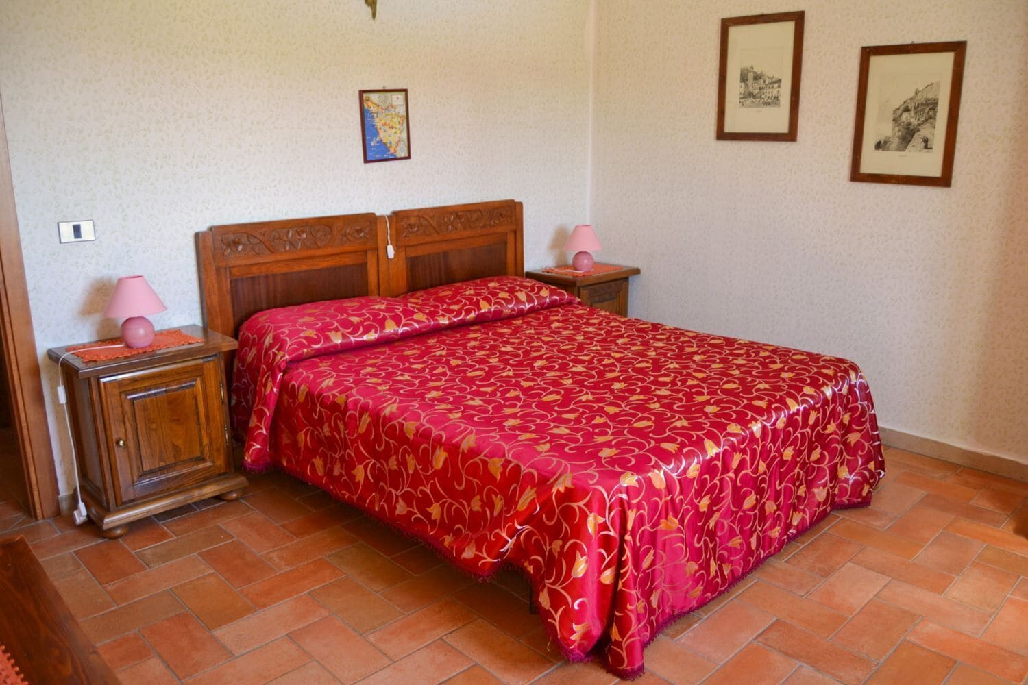 Een slaapkamer met een groot bed, een houten hoofdbord, twee nachtkastjes en een klein kastje.