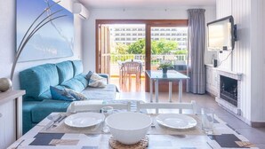 A modern living room with a sofa, dining table, and a fireplace. - Apartment near beach and nightlife, perfect for fun holidays (Alcúdia)