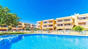 A hotel with a swimming pool, multiple balconies, and a clear blue sky. - Apartment near beach and nightlife, perfect for fun holidays (Alcúdia)