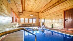 Una cabaña de madera con piscina, paredes de madera y una puerta.