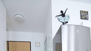 A modern kitchen with a stainless steel refrigerator, a wooden door, and a wall clock. - Victus Apartamenty - Cadena 3 (Sopot)