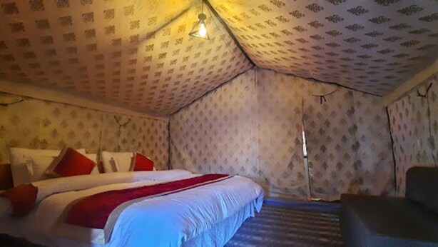 A room with a bed, a chair, and patterned wallpaper. - TIH P3 Camp - Pangong (Leh)