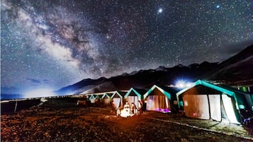 Cielo stellato con la Via Lattea ben visibile sopra una fila di tende.