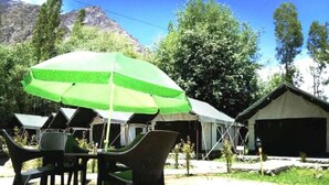 A campsite with tents, a table with chairs, and a mountain in the background.