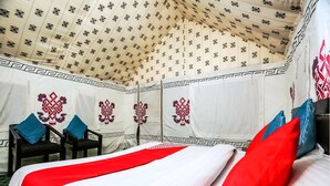 A tent-style room with a bed, pillows, and a chair.