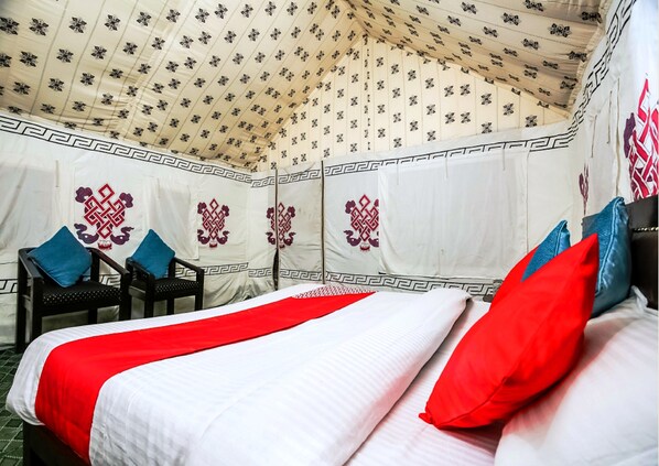 A tent-style room with a bed, pillows, and a chair.