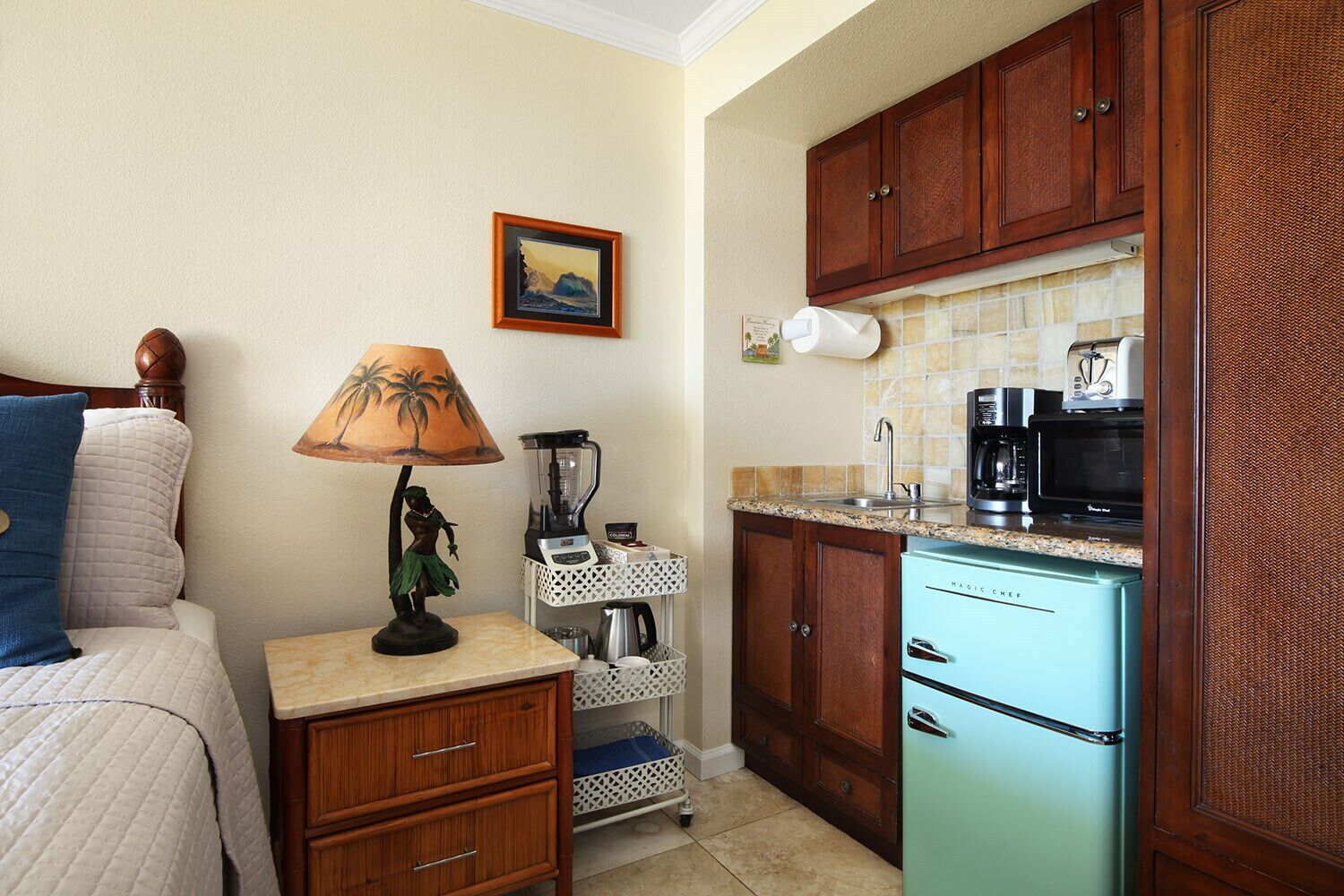 Cocina compacta con refrigerador, microondas, cafetera y un lavamanos pequeño.