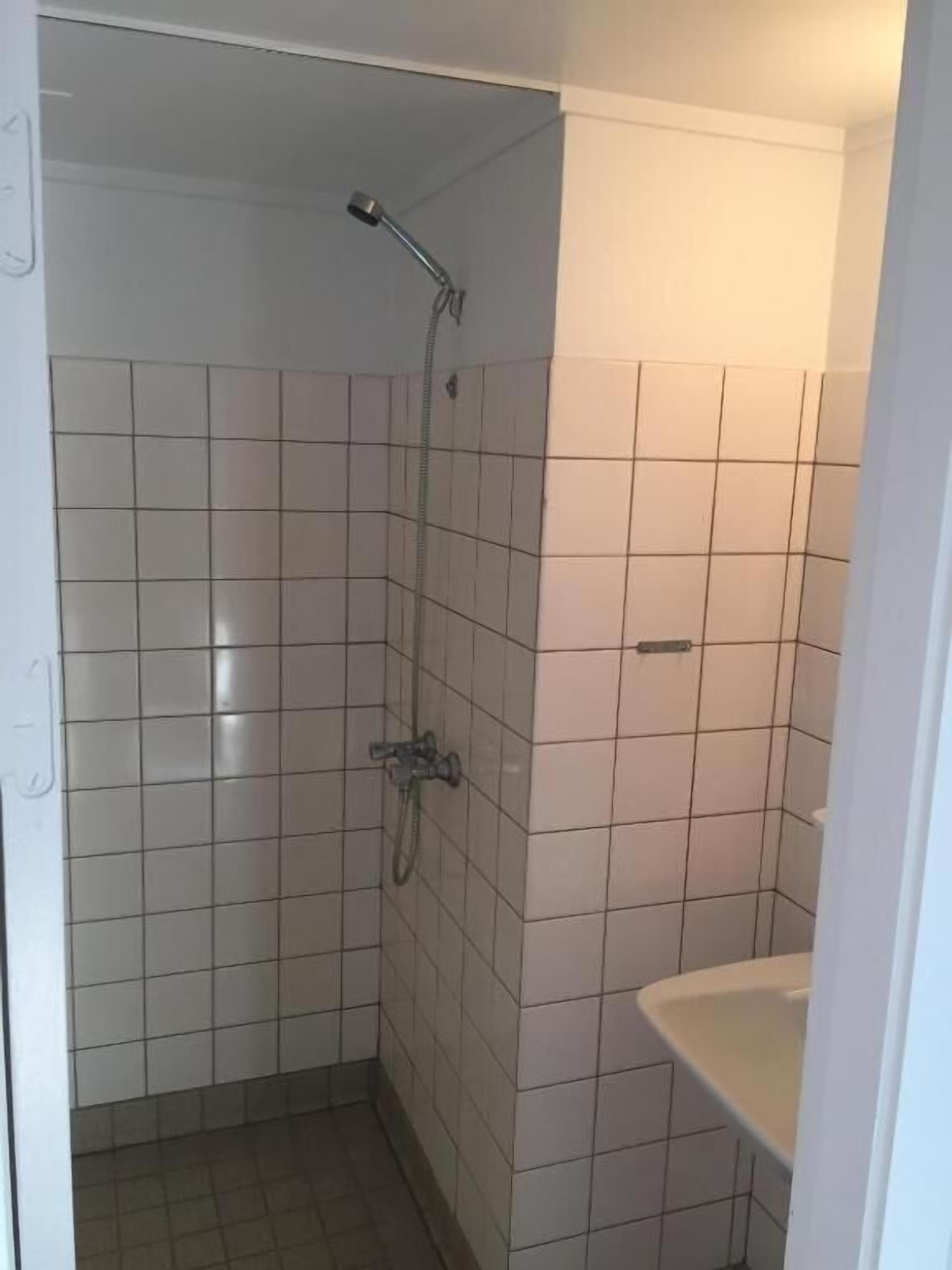 A small, tiled bathroom with a shower, a sink, and a toilet.