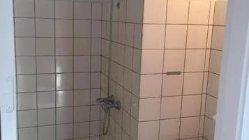 A small, tiled bathroom with a shower, a sink, and a toilet.