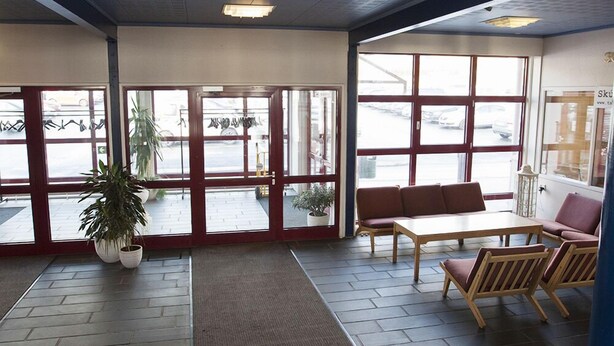 Een ruime lobby met een groot raam, een receptiebalie en een zithoek.