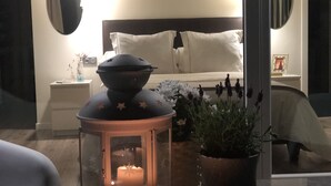 Una camera da letto con un letto, comodini, una pianta in vaso e una candela accesa.