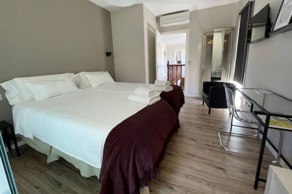 A hotel room with a large bed, a desk, and a mirror.