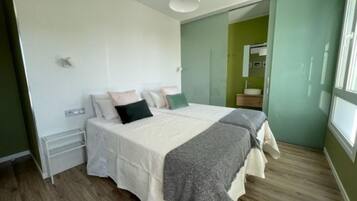 A bedroom with a bed, bedside tables, a mirror, and a window.