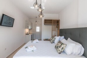 Ett modernt hotellrum med en stor säng, en garderob i trä, en liten köksdel och en inramad tavla på väggen.
