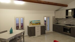 Una cocina moderna con comedor, que presenta un cuadro en la pared, una pequeña isla y vistas a través de puertas de vidrio.