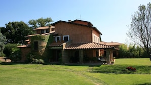 A two-story house with a tiled roof, a stone facade, and a covered porch. - Villa Iris (Corchiano)