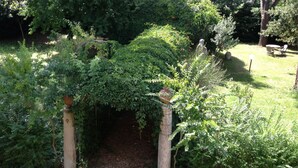A garden with a stone archway surrounded by lush greenery. - Villa Quattro Mori (Arezzo)