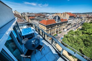 Une terrasse sur le toit avec un jacuzzi, des sièges extérieurs et une vue sur le paysage urbain.