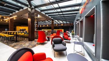A spacious indoor area with high ceilings, modern seating, and a large windowed wall.