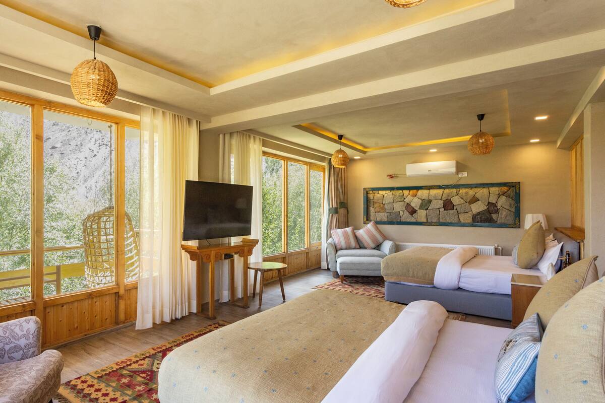 A spacious room with a large bed, a sofa, a TV, and a stone wall artwork.