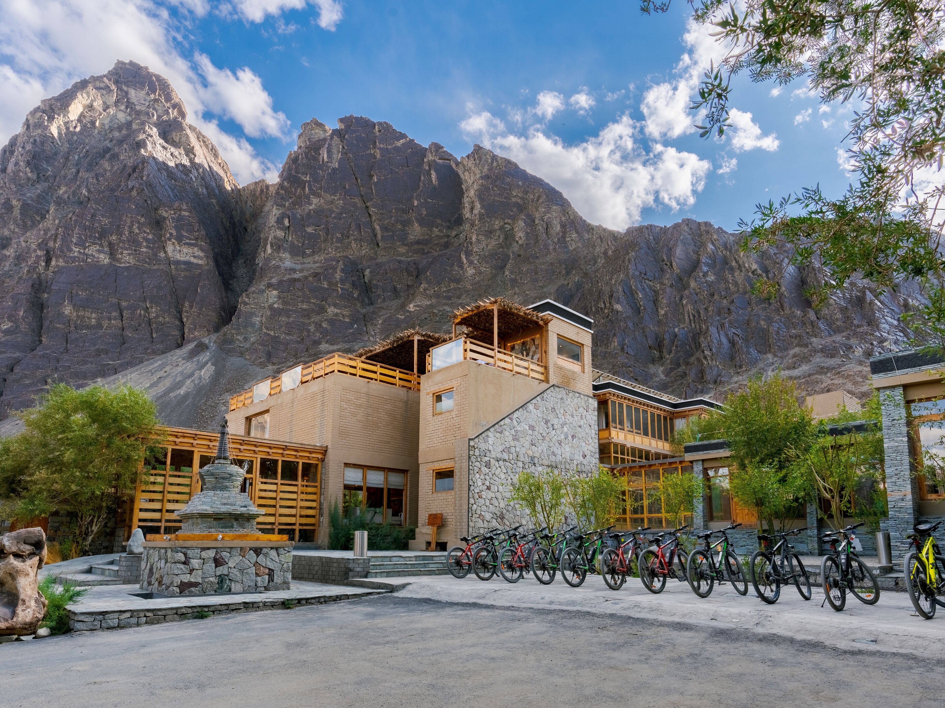 A modern building with a stone facade, wooden balconies, and a bicycle parking area in front.