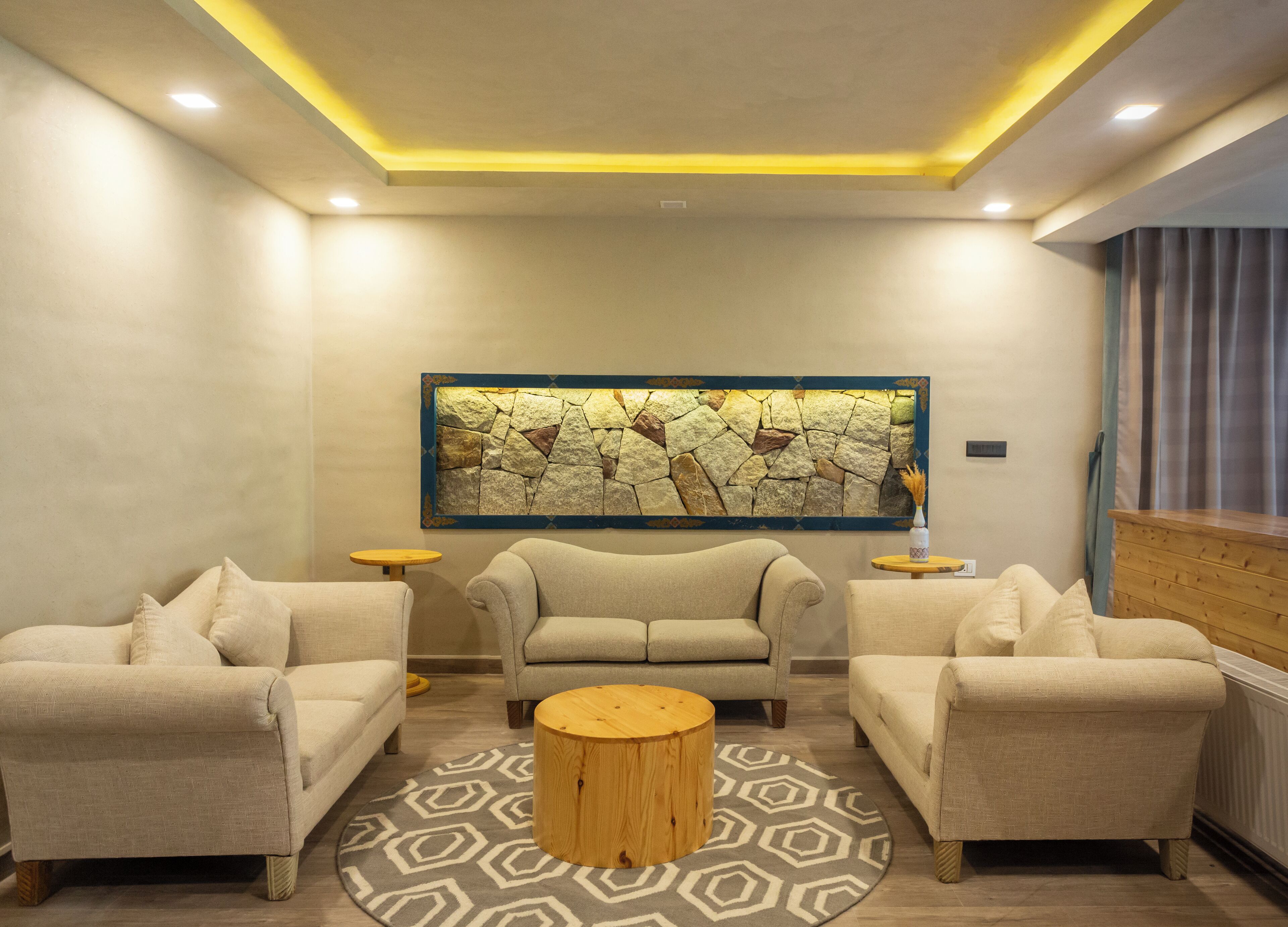 A modern living room with two sofas, a coffee table, and a stone wall art piece.