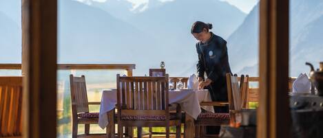 Un restaurant doté de meubles en bois et offrant une vue sur la montagne.