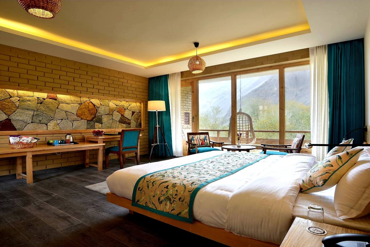 A hotel room with a large bed, a desk, and a view of the outdoors.