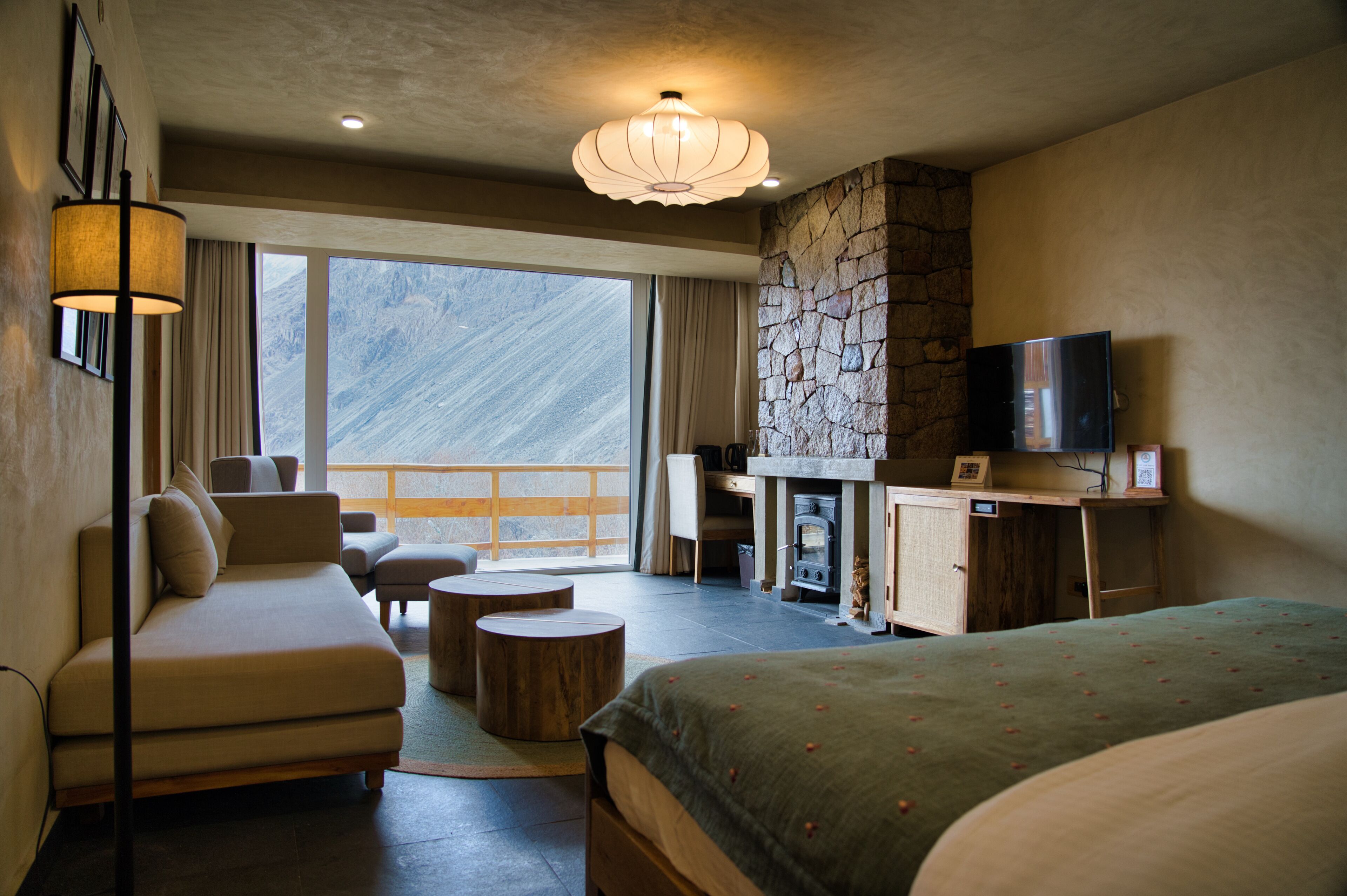 Una habitación de hotel con sofá, cama, escritorio con televisor y chimenea.