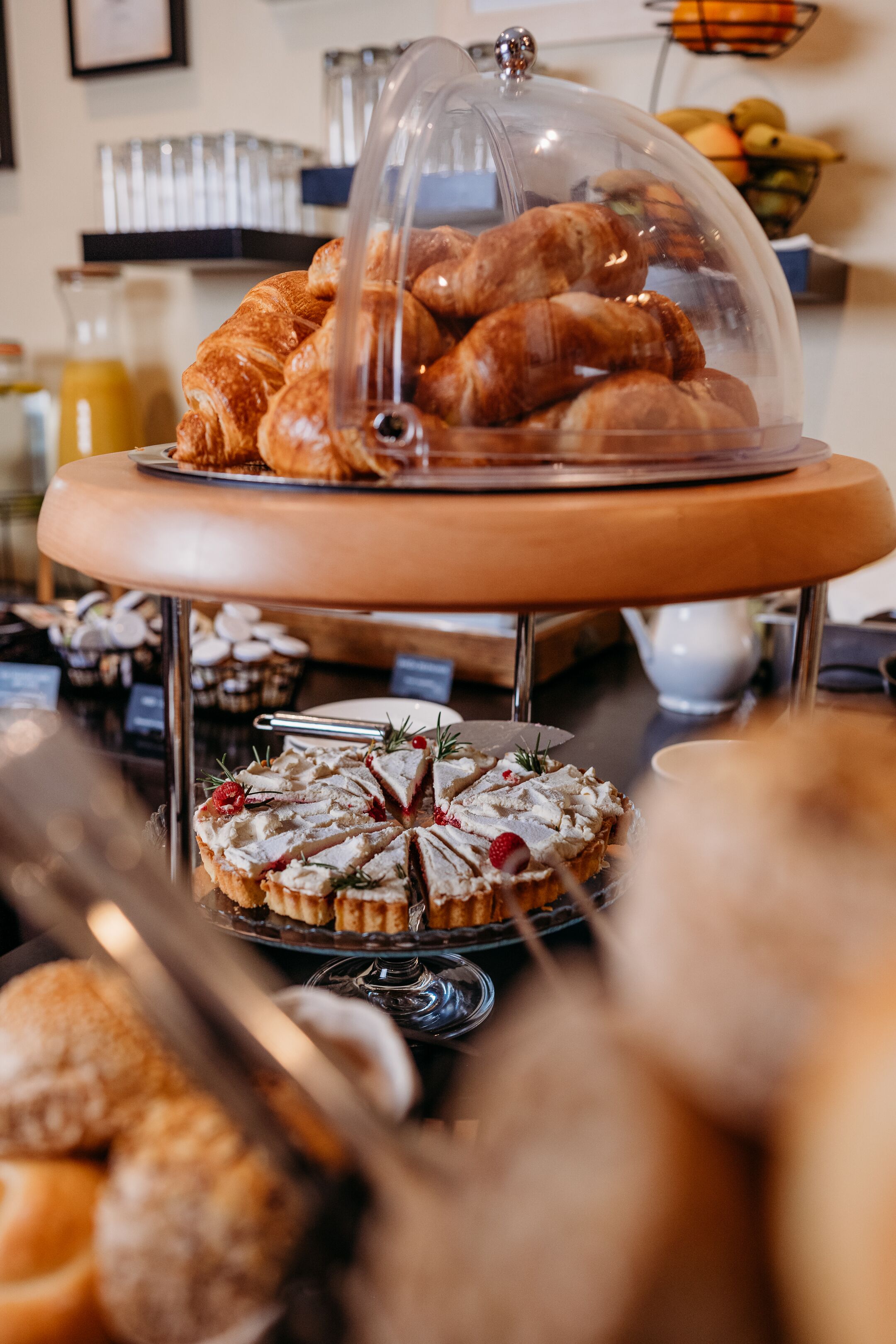 Een ontbijtbuffet met croissants, een fruitschaal en diverse gebakjes.