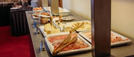 A buffet table with various food items and utensils.