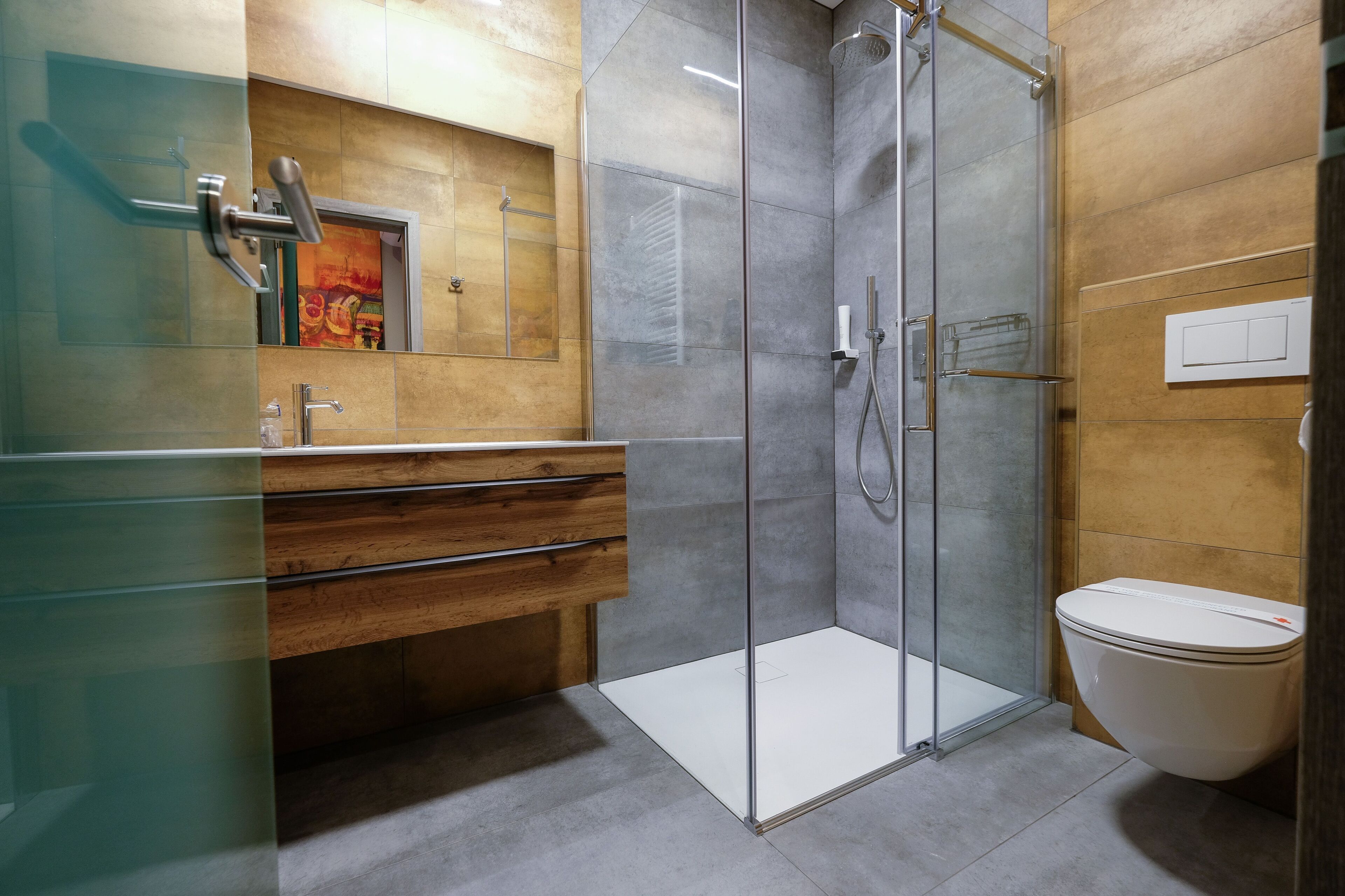 A modern bathroom with a glass shower enclosure, a wooden vanity, and a toilet.