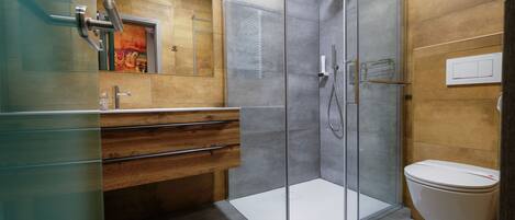 A modern bathroom with a glass shower enclosure, a wooden vanity, and a toilet.