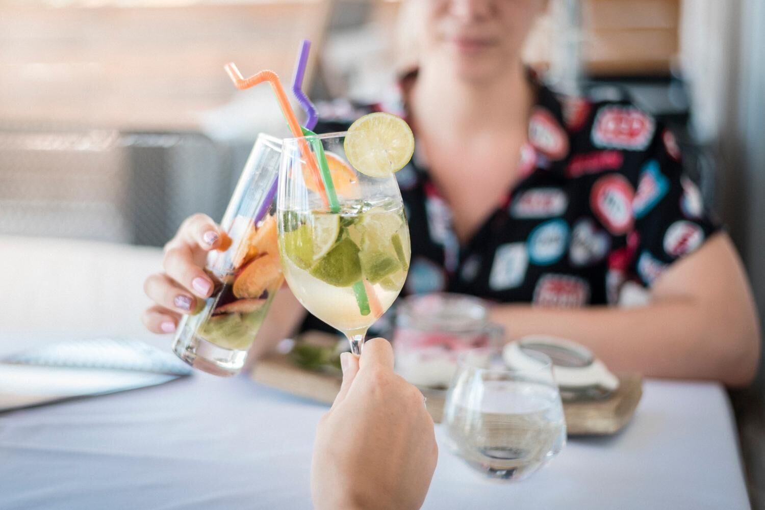 Dos personas sosteniendo vasos de una bebida de lima y menta con pajitas.