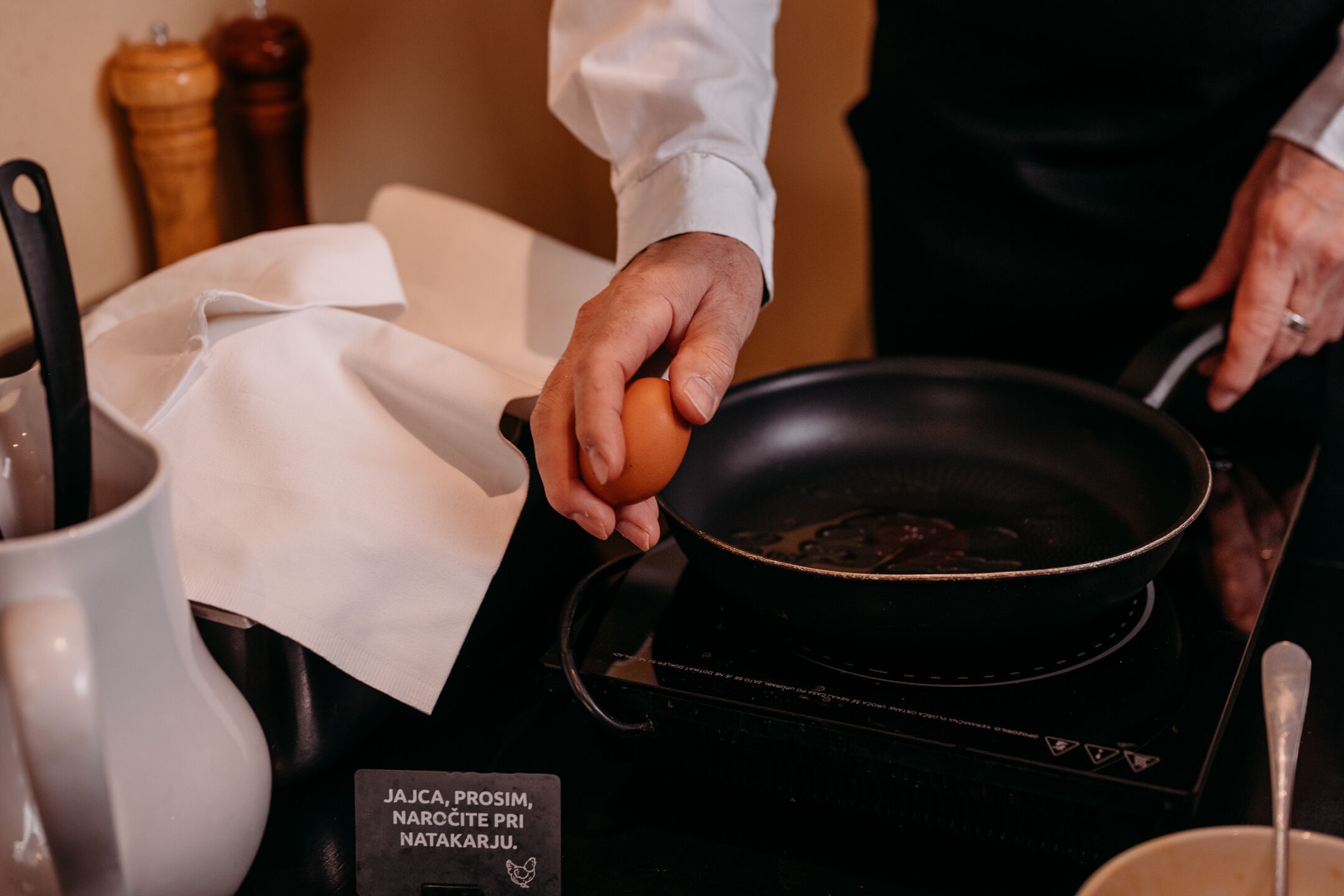 A person cooking an egg in a pan on an induction stove.