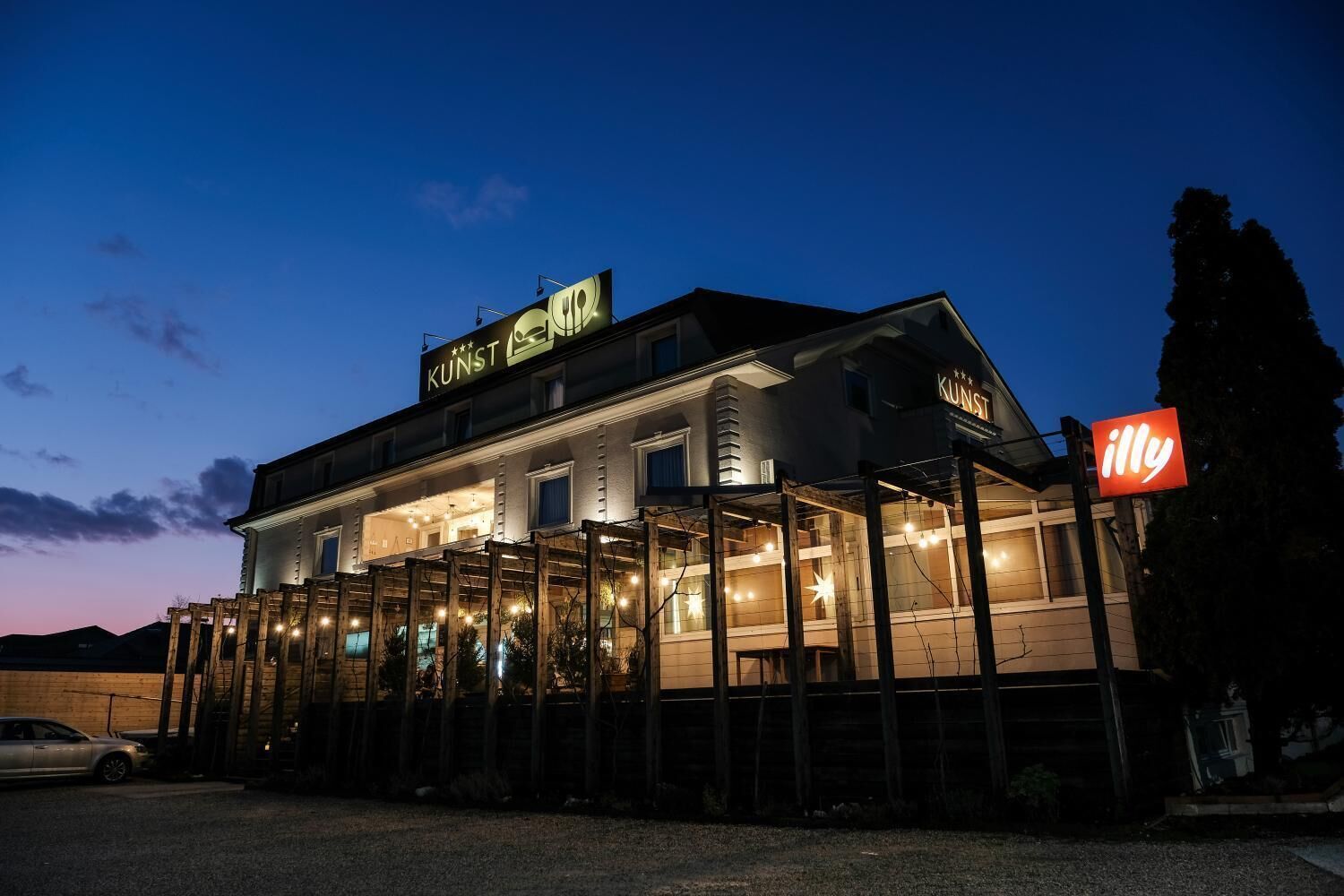 Un bâtiment sur lequel on peut lire les mots « KUNST » et « illy », indiquant qu’il s’agit d’un restaurant ou d’un café.