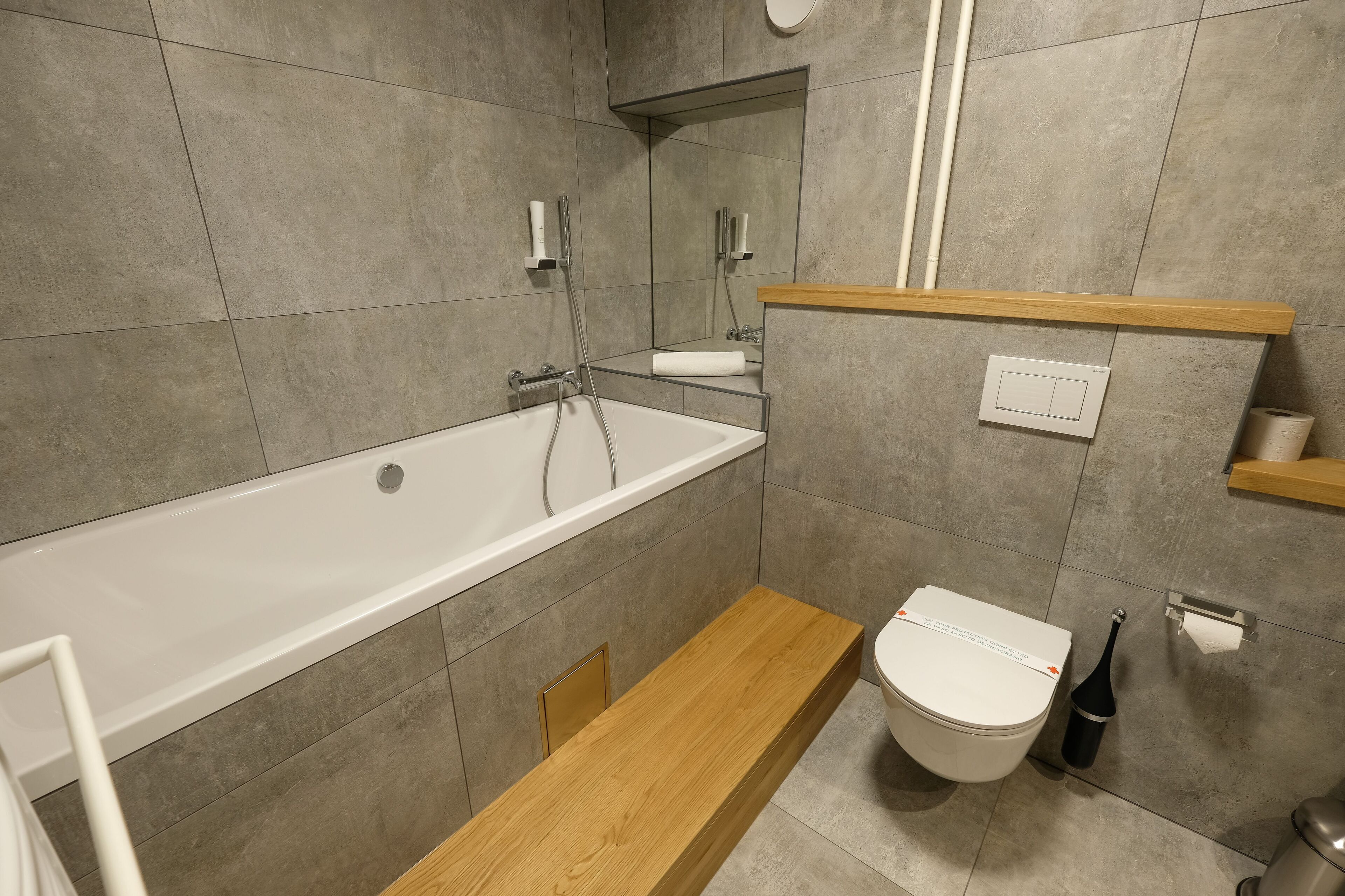 Ein modernes Badezimmer mit Badewanne, Toilette und einem Holzbidet.