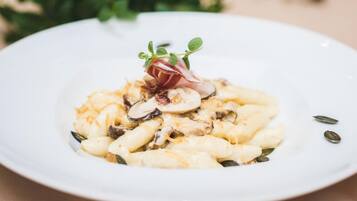 A plate of pasta with mushrooms and a garnish of microgreens and a red leaf.