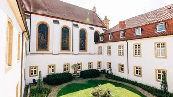 A courtyard with a fountain, surrounded by white buildings with arched windows and red-tiled roofs.