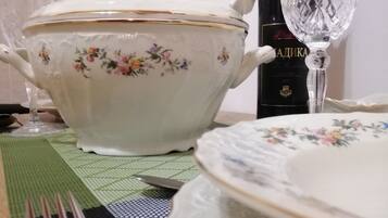 A dining table with a floral-patterned white bowl, a wine bottle, and a wine glass.