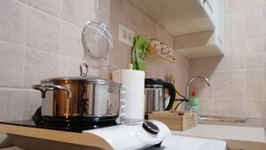 Una cocina con estufa, olla, cafetera y una caja de té.